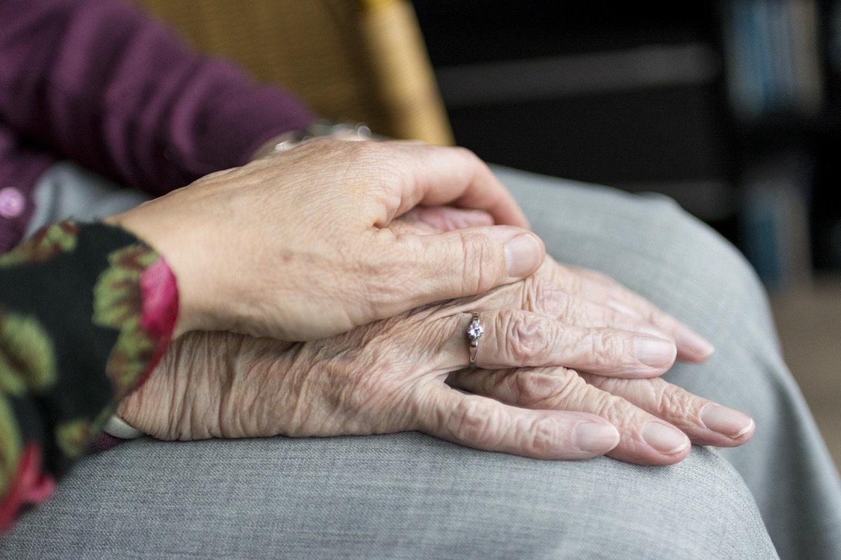 A caregiver holding an elderly person's hands